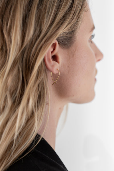 Gold Mini Crossover Earring worn in ear, model has blonde tousled hair