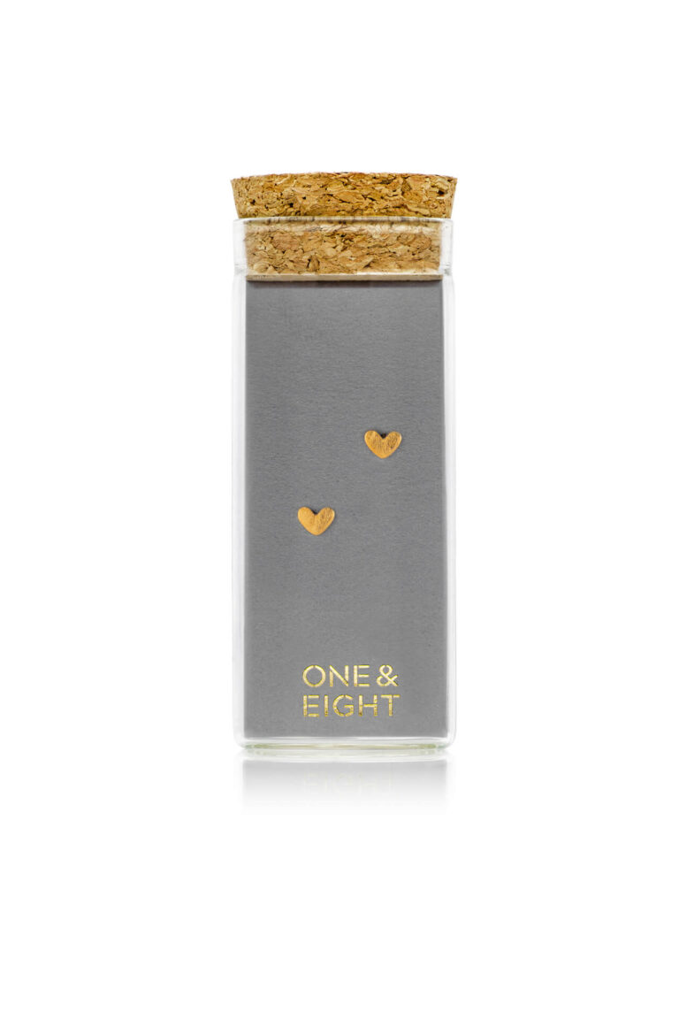 Gold Tiny Heart Stud Earrings on grey card in a glass bottle with cork lid