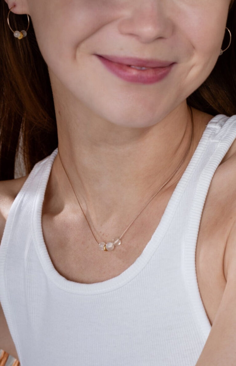 Our smiling model with red hair wears Moonstone Cord Necklace and Moonstone Gold Hoop Earrings and a white tank top