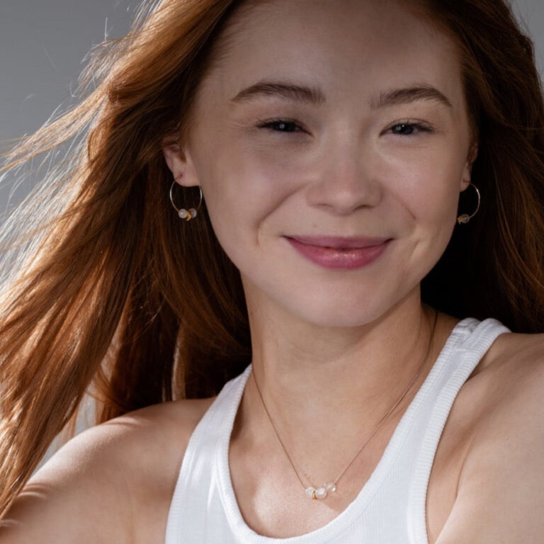 Our smiling model with red hair wears Moonstone Cord Necklace and Moonstone Gold Hoop Earrings and a white tank top