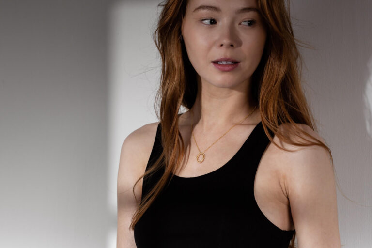 Model with ginger hair wears the Gold Verona Necklace and a black tank top