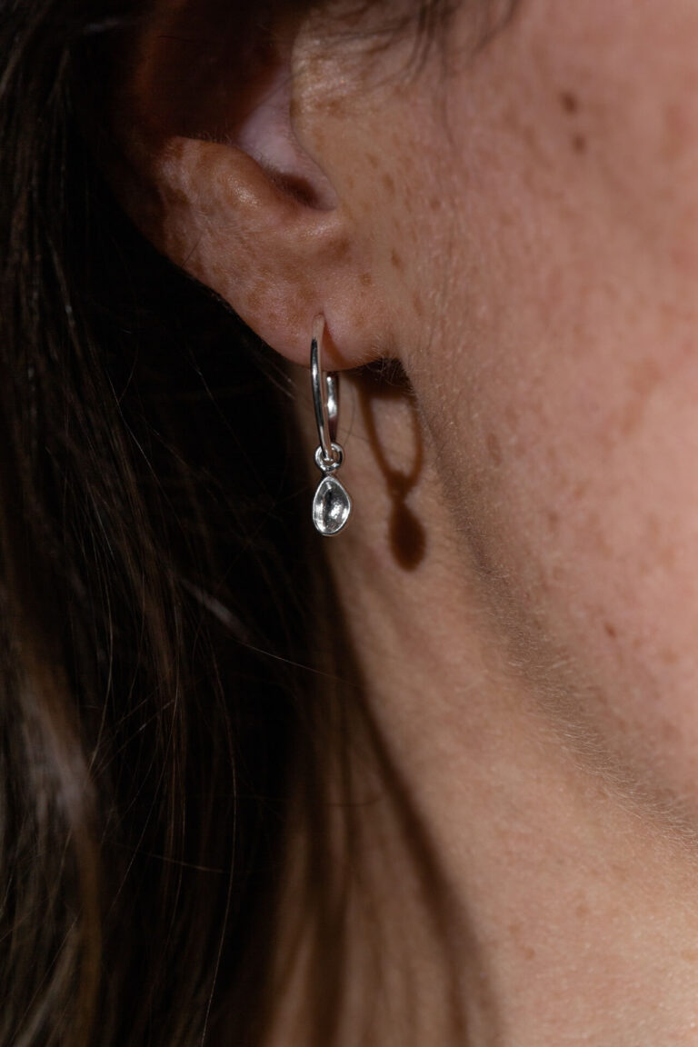 Close up of Silver Darcie Drop Earrings worn by model with dark hair and freckles