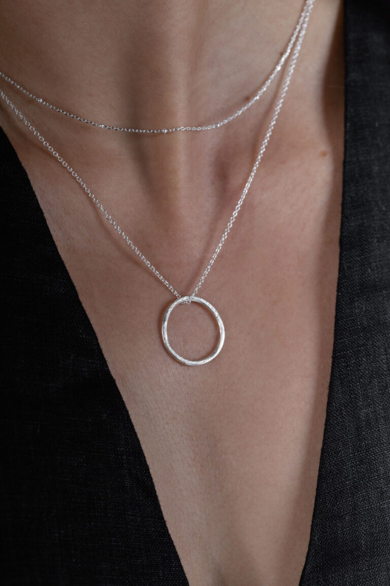 Close up of model wearing Silver Hoop Larissa Necklace with black v-neck top