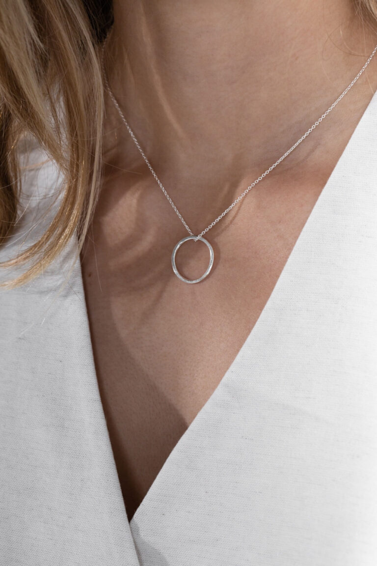 Close up of model wearing Silver Hoop Larissa Necklace with white v-neck top