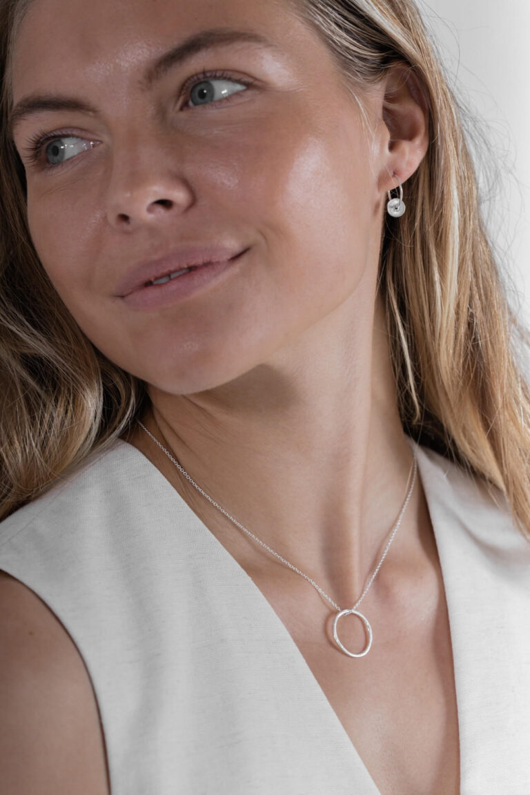 Model with blonde hair wearing Silver Hoop Larissa Necklace and Silver Disc Sorrel Hoop Earrings with black v-neck top