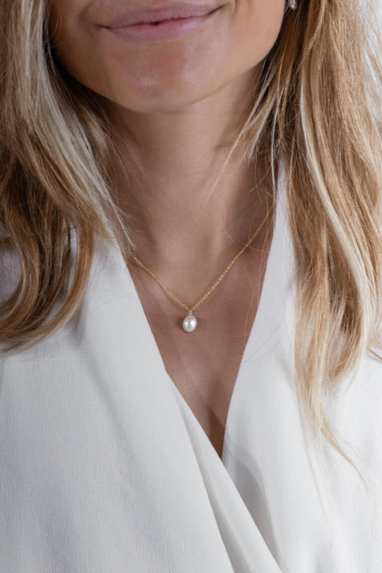 Model with blonde hair wears Gold Pearl Necklace and a white blouse