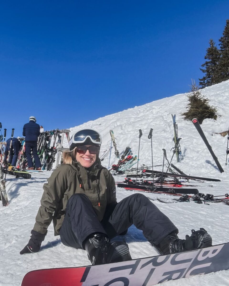 Snowboarder sitting in the snow, smiling.